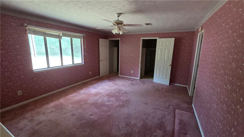 Crown molding and wide windows frame this spacious bedroom.