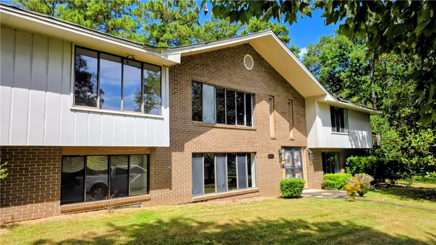 Mid-century architectural lines blend brick veneer and vertical siding in a serene wooded setting.