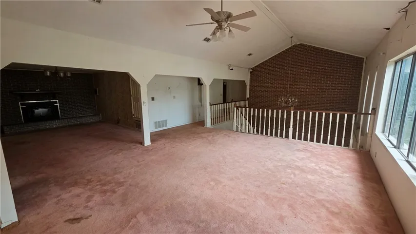 A spacious layout showcases vaulted ceilings, a brick feature wall, and large windows.