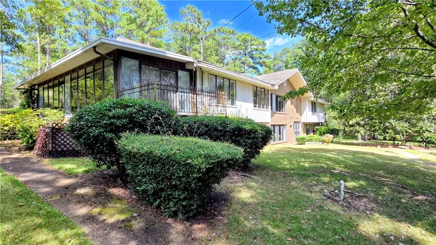 Mature trees and neat hedging frame a multi-level home nestled on a grassy lawn.