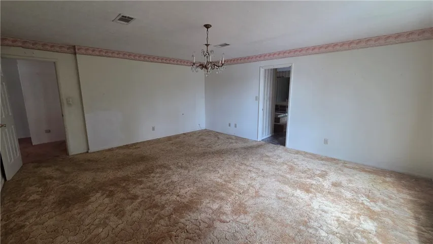 A spacious room features plush wall-to-wall carpeting and detailed crown molding.