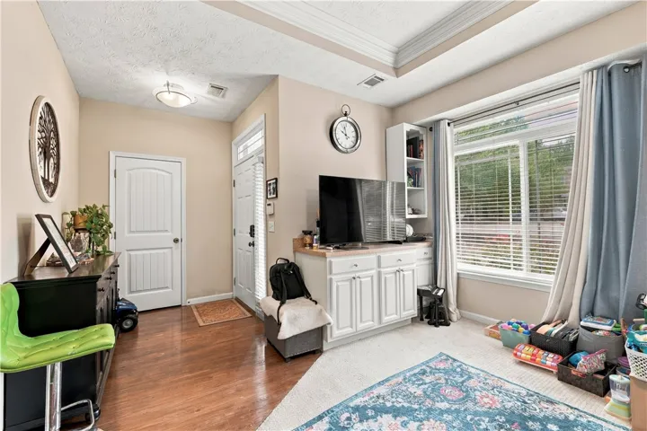 Rich wood floors meet soft carpet beneath a classic tray ceiling in this versatile space.
