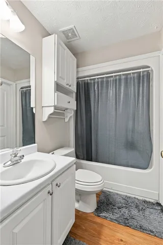 Rich wood-inspired flooring pairs with a classic white vanity in this functional bathroom layout.