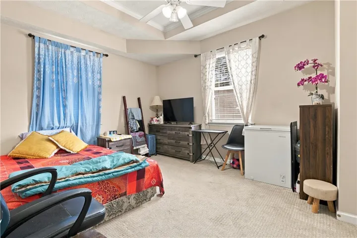 Soft carpet and a tray ceiling define this comfortable bedroom space.