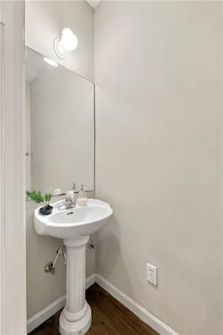 A classic pedestal sink sits on rich hardwood flooring in this cozy powder room.