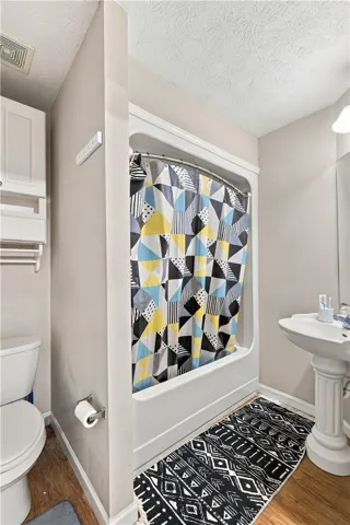 A pedestal sink and classic tub shower combo maximize the space in this bathroom.