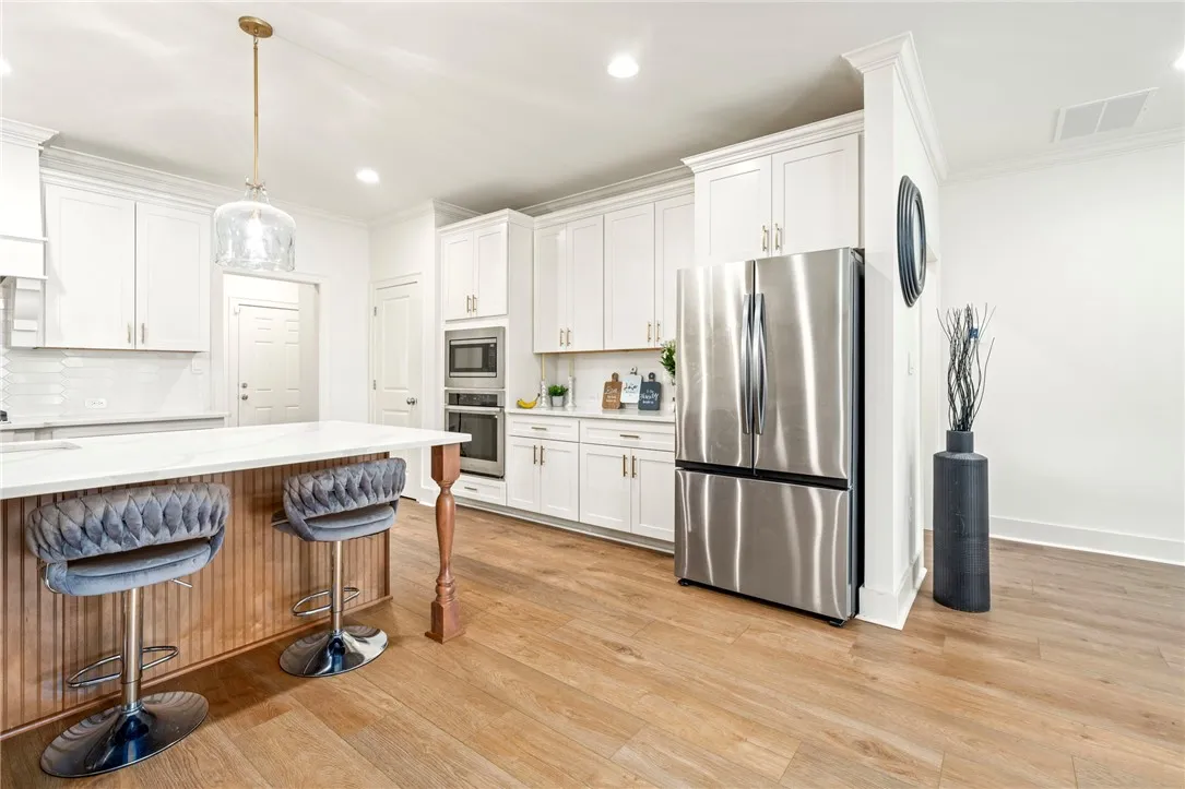 Rich wood floors and clean-lined white cabinetry define this bright modern kitchen space.