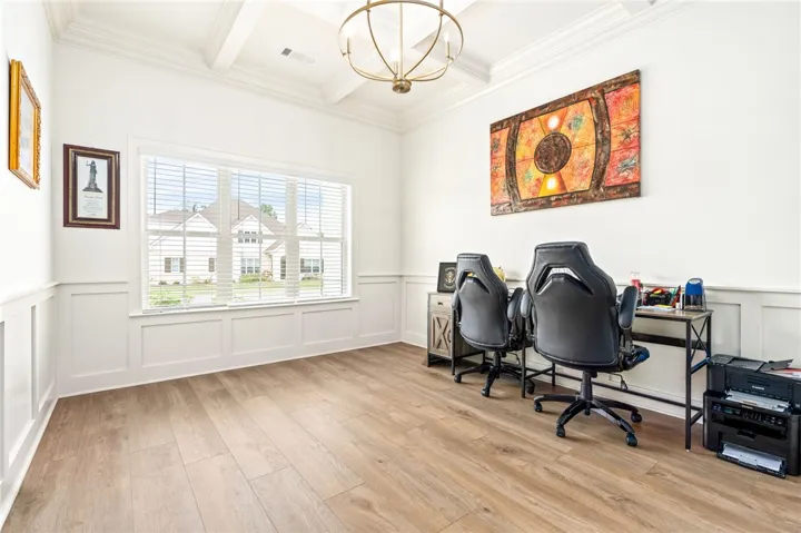 Elegant wainscoting and a classic coffered ceiling elevate this light-filled study with warm wood flooring.