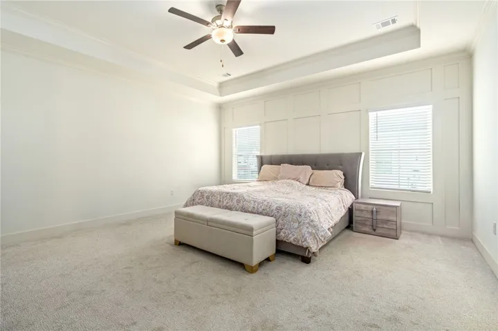 Elegant tray ceilings and textured wall paneling elevate this restful bedroom retreat.
