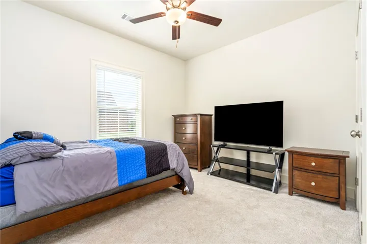 A quiet bedroom features plush carpeting and a large window looking out toward the yard.