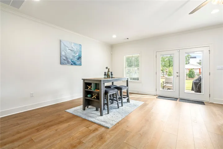 Warm wood flooring and detailed crown molding elevate this versatile dining space.
