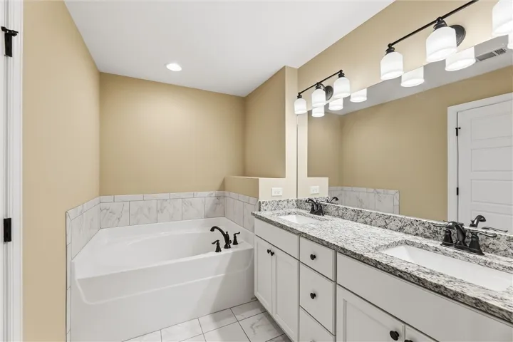 A spacious double vanity and a deep soaking tub complete this modern bathroom space.