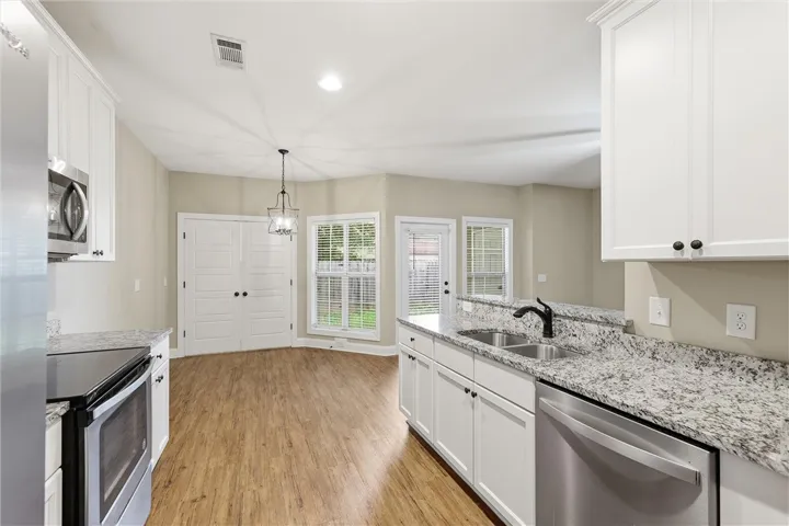 Gleaming stone countertops and warm wood floors anchor this open culinary and dining space.