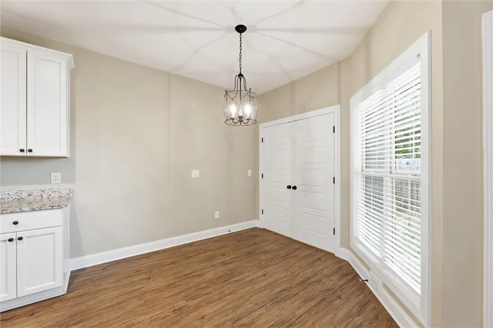 Gleaming hardwood floors run through a sunlit breakfast area framed by classic white moldings.