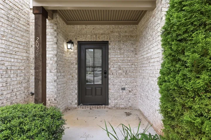 White brick walls frame a covered entry featuring a classic paneled front door.