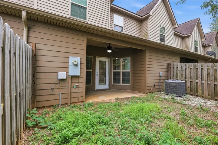 A sheltered back patio opens to a private fenced yard with natural lawn.