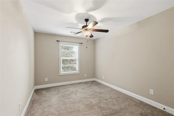 Soft carpeting underfoot defines this neutral space, complete with a classic window and molding details.