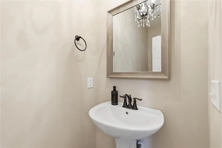 A classic pedestal sink sits beneath a framed mirror in this elegant powder room.