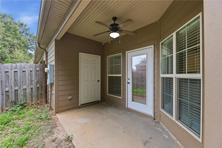 A covered concrete patio provides a functional outdoor transition framed by large multi-pane windows.