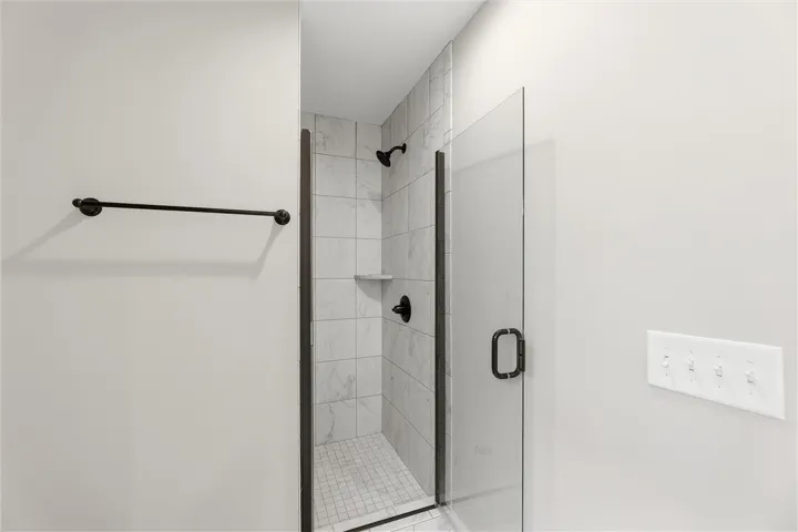 Clean lines define a modern walk-in shower lined with elegant floor-to-ceiling tile work.