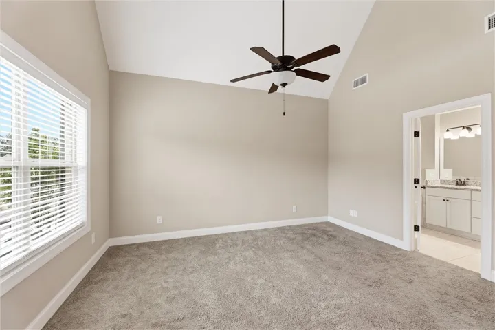 Plush carpeting and vaulted ceilings define this peaceful primary bedroom suite.