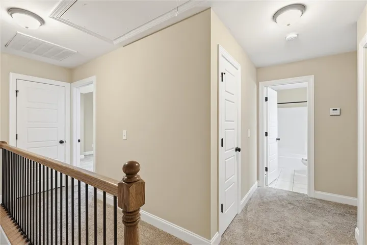 An upper-level landing connects several rooms with classic wooden railings and neutral carpeting.