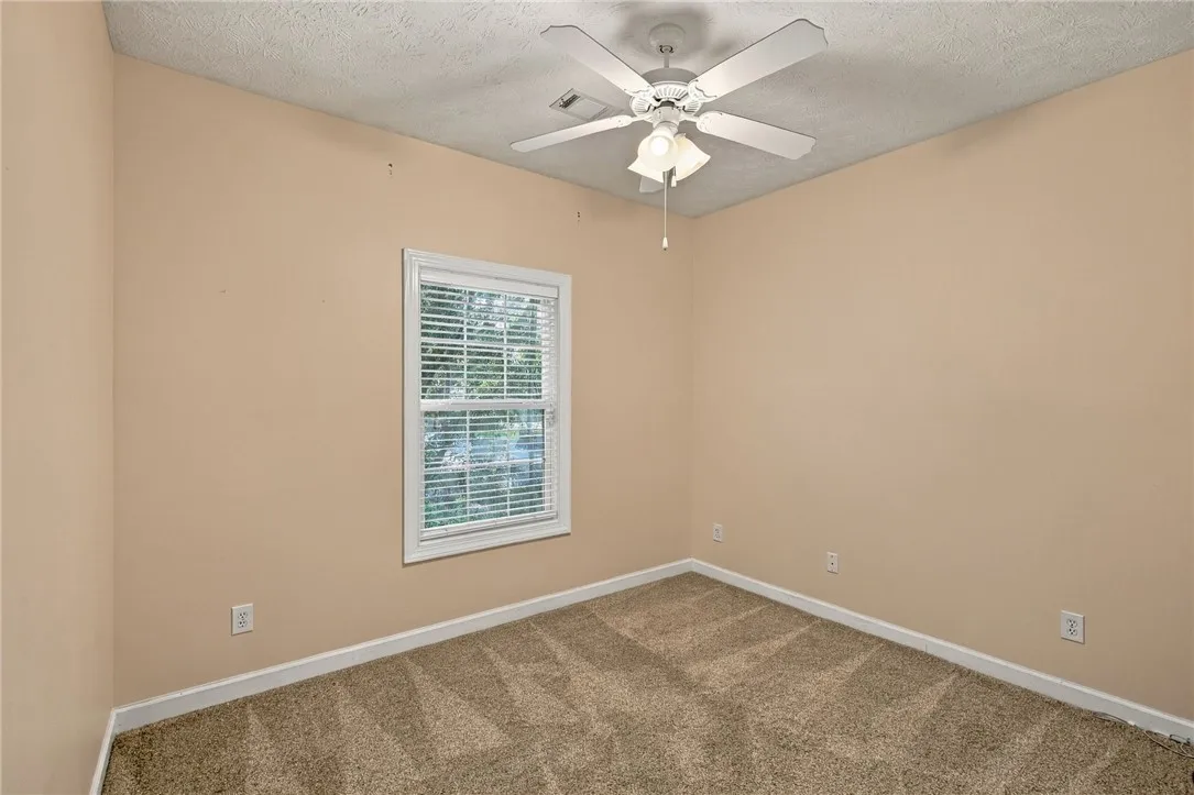A single window provides natural light to this carpeted bedroom.