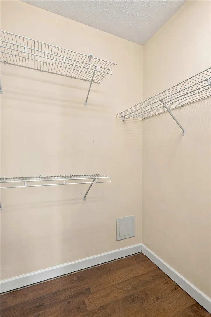 An organized walk-in closet features built-in wire shelving and durable wood flooring.