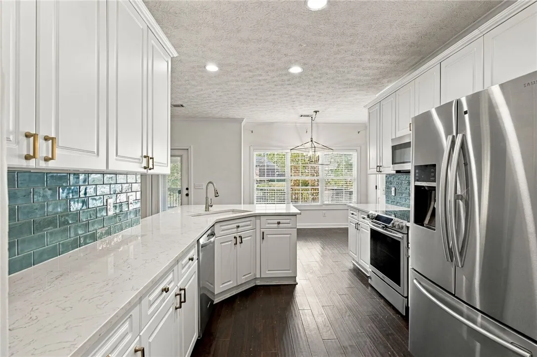 Polished stone countertops complement the vibrant tile backsplash and rich hardwood flooring in this kitchen.