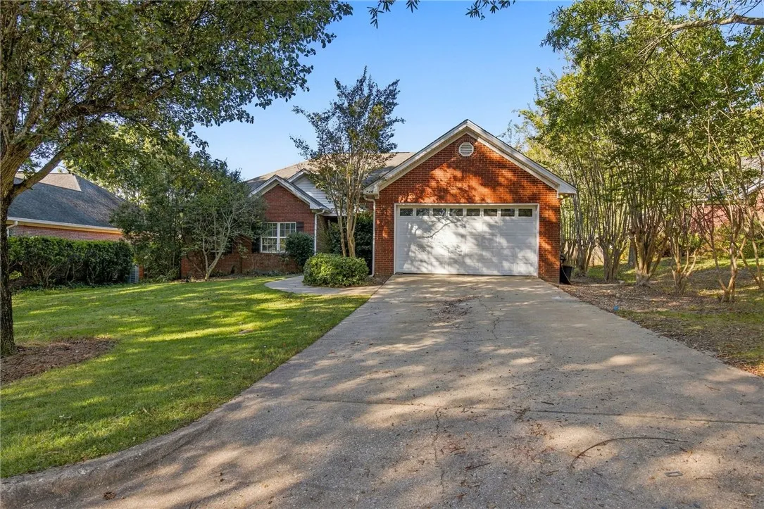 Mature trees frame a classic brick exterior complete with a spacious front-facing garage.