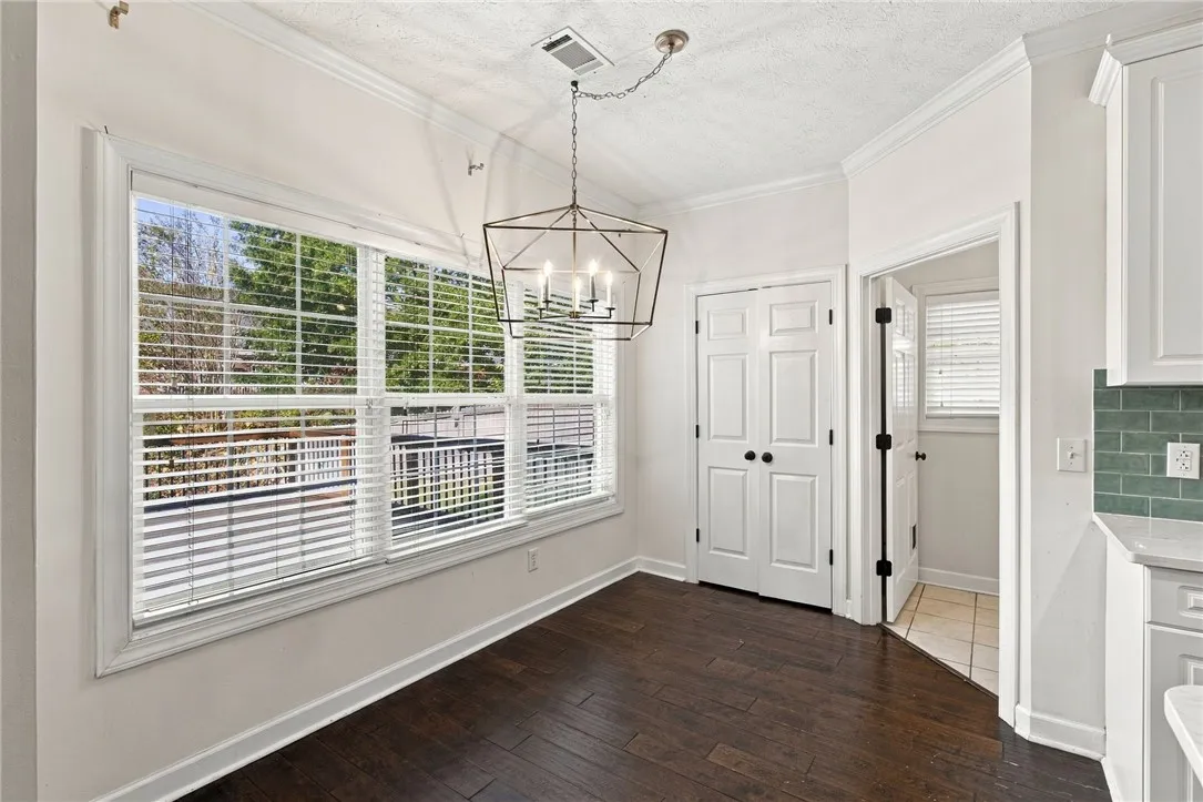 Rich hardwood flooring and crown molding frame this inviting breakfast area with large windows.