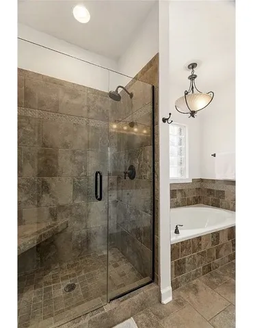 Rich tilework frames a glass-enclosed walk-in shower alongside a deep soaking tub.