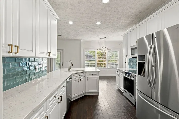 Polished stone countertops complement the vibrant tile backsplash and rich hardwood flooring in this kitchen.