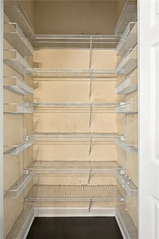 Ample built-in wire shelving provides efficient storage space inside this deep walk-in pantry.