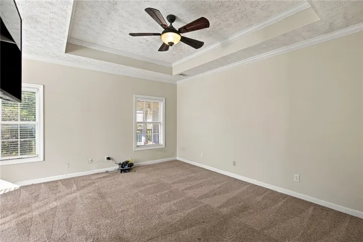 Plush carpeting anchors this comfortable space featuring a detailed tray ceiling and classic crown molding.