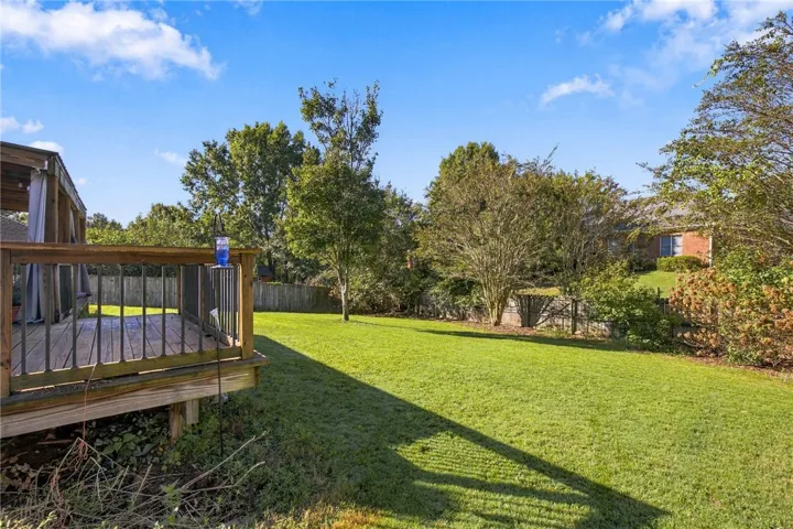 A spacious wooden deck overlooks a grassy yard enclosed by privacy fencing.