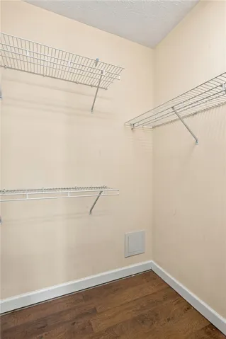 An organized walk-in closet features built-in wire shelving and durable wood flooring.