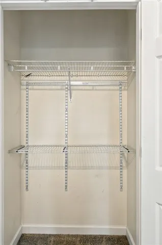 Organized storage potential awaits within this versatile reach-in closet featuring adjustable wire shelving and carpet flooring.