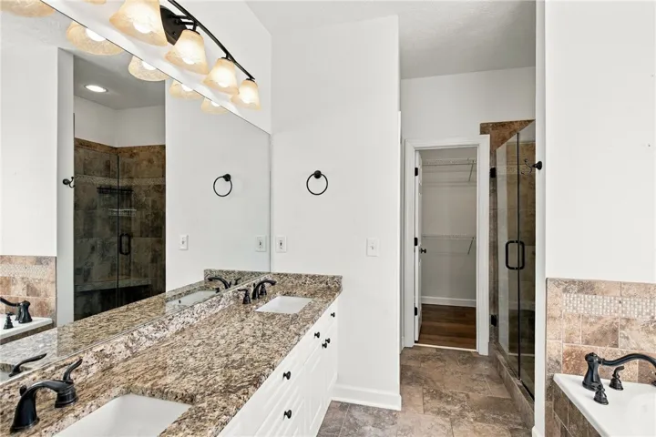 Polished granite counters and natural stone tile floor elevate this master bathroom.