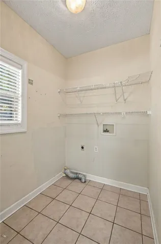 A dedicated laundry space features functional wire shelving, neutral tiled flooring, and a bright window.