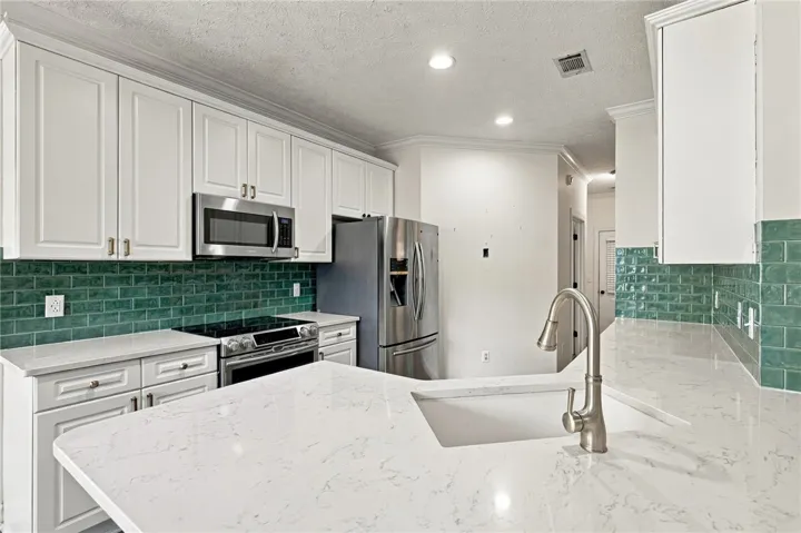 Polished stone countertops pair elegantly with tile backsplashes and classic white cabinetry.