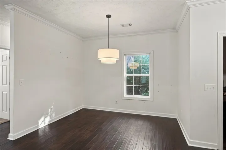 Rich hardwood flooring and classic crown molding anchor this versatile dining area.