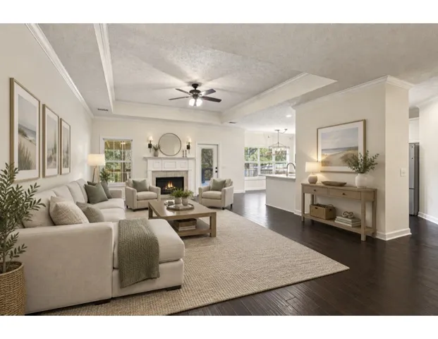 *Digitally Staged*Rich dark wood floors anchor an airy living space under a detailed tray ceiling.