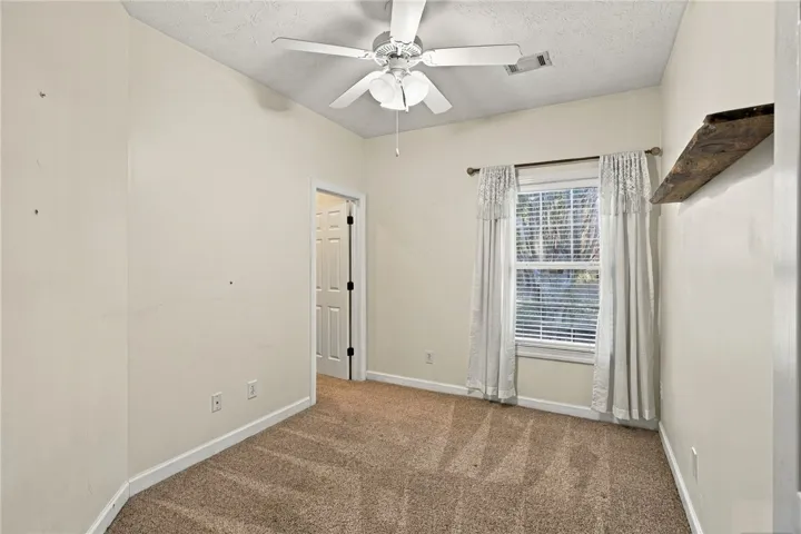 A single window provides natural light to this room finished with soft carpeting.