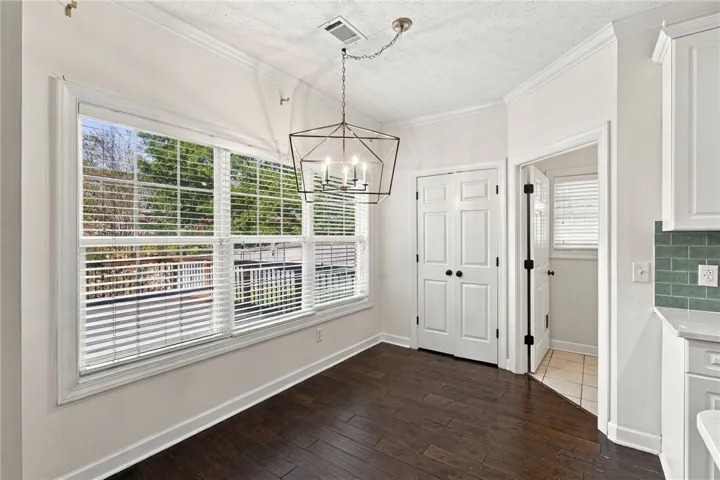 Rich hardwood flooring and crown molding frame this inviting breakfast area with large windows.