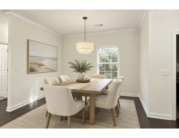 *Digitally Stage*Crown molding and rich hardwood flooring frame this welcoming dining area near a window view.