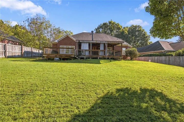 A spacious grassy lawn rolls toward the rear deck of this classic brick home.
