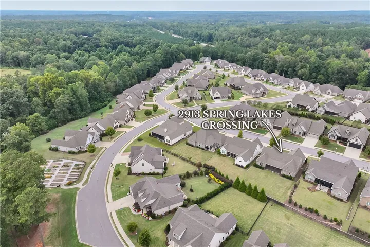 An aerial perspective showcases a neat suburban neighborhood nestled against a dense forest.