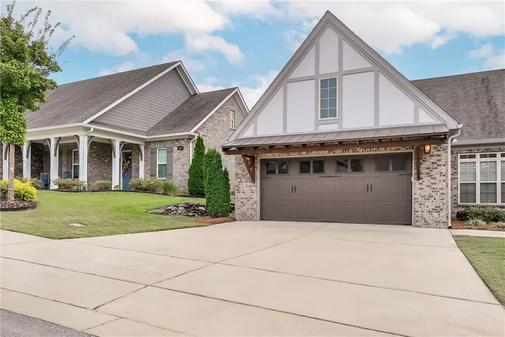 A spacious concrete driveway leads to an elegant attached garage featuring classic Tudor architectural details.