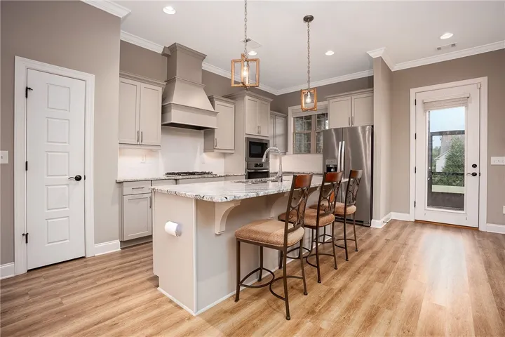 Polished stone counters, custom cabinetry, and warm wood flooring define this well-appointed kitchen workspace.
